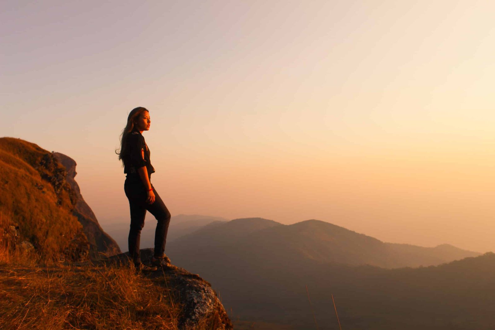 Hipster young girl with backpack enjoying sunset on peak of fogg